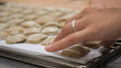 Artisan hands meticulously crafting delicate fresh ravioli in a warm bustling kitchen preparing a delightful Italian culinary masterpiece with focused dedication and passion