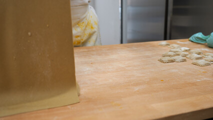 Passionate chef meticulously crafting artisanal Italian pasta shapes by hand on a flour-dusted...