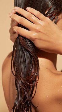 Close-up of a woman running her hands through her wet, healthy hair