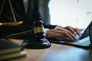 Close-up of a lawyer working on a contract with a gavel placed on a toy car, symbolizing automobile law and justice.