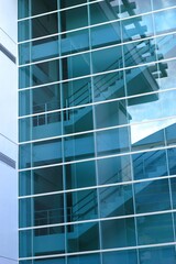 Modern glass building facade with reflections of staircase and structure