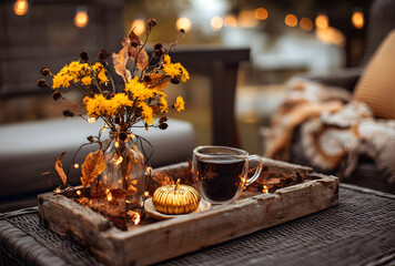 Still life of autumn themed items on a wooden tray with a cup of coffee and yellow flowers vase