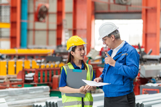 Mechanical engineer and female technician inspecting machinery in factory