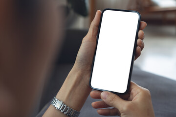 Cell phone blank white screen mockup. Woman hand holding, using mobile phone at coffee shop, empty space for social media marketing, mobile app design, business technology
