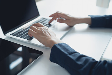 Close up, business woman hand typing, working on laptop computer with digital tablet on office table, surfing the internet, searching the information, business technology, remote work concept