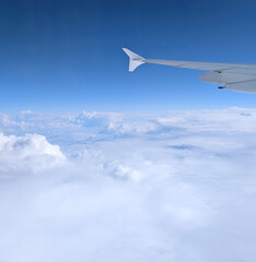 fluffy clouds seen from a plane in flight and a piece of the wing