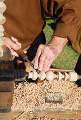 master craftsman hand shaping timber on vintage lathe machine with carving tool
