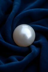 White pure pearl on dark blue velvet satin fabric with abstract round elements, lighting studio.