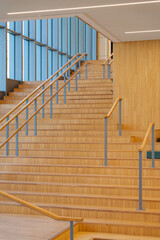 Wooden staircase with metal railings ascends towards a bright, open space, inviting exploration and upward movement.
