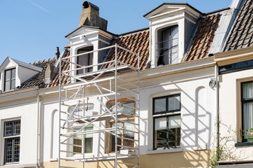 Scaffolding on a white building under a clear sky, indicating renovation or repair work in progress.