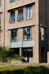 Brick building with open windows and flowerbeds, showcasing simple architecture and natural light.