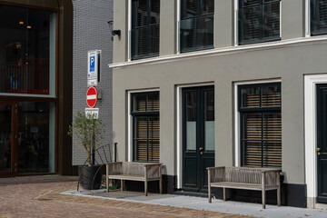 Urban gray building with benches and dark green doors and window frames on a sunny day in a city.