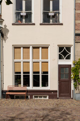 Charming building facade with a bench, textured windows, and brick pavement in soft sunlight.