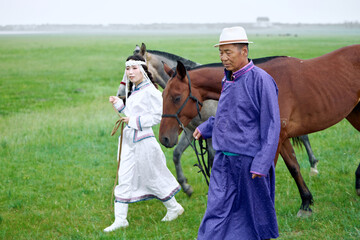 Mongolian herders father and daughter grazing on the grassland