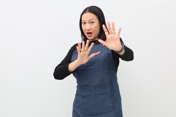 Young Asian woman wearing apron on white background with disgust, displeasure and fear expression...