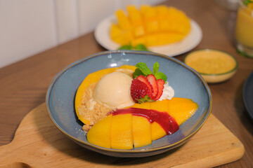 Mango Dessert: A culinary masterpiece featuring fresh, vibrant mango slices elegantly arranged with creamy ice cream, strawberries, and a drizzle of sweet sauce, offering a tempting visual feast.