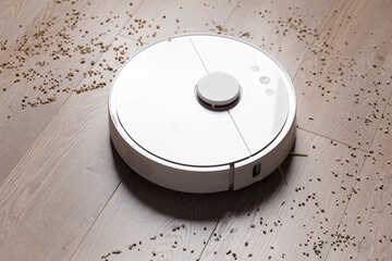 Smart robot vacuum cleaner removes scattered debris from the laminate floor.
