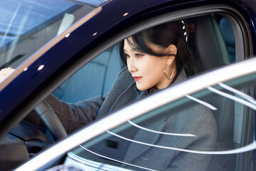 Asian beauty test driving a car in a 4S car dealership