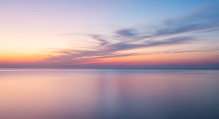 Obraz premium Soft pastel sunset over a tranquil ocean with gentle waves and a gradient sky