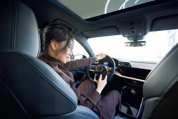 Asian beauty test driving a car in a 4S car dealership