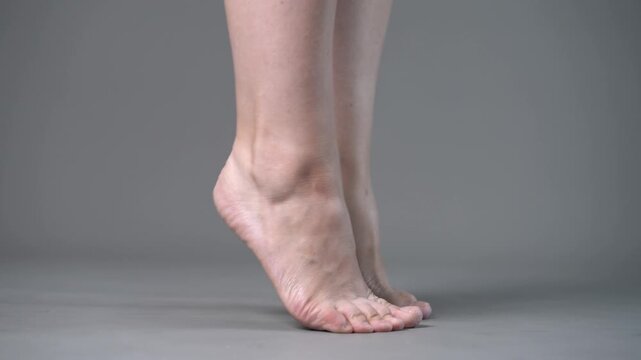 Individual leg training on a gray studio background, bare feet, demonstrating foot position and stability