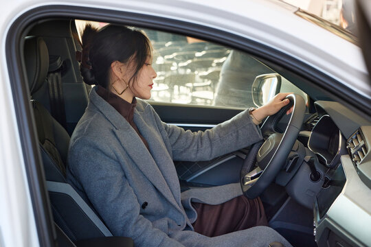 Asian beauty test driving a car in a 4S car dealership