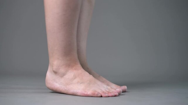 Individual leg training on a gray studio background, bare feet, demonstrating foot position and stability