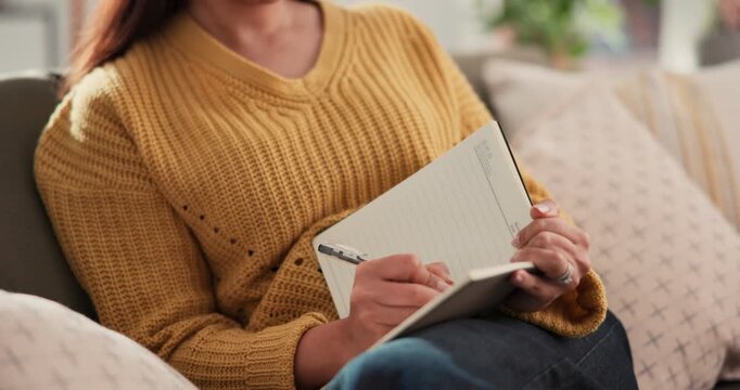 Woman, hands and writing with book for diary reminder, checklist or agenda on sofa in home. Female person, planner or writer with notebook, pen or notes for daily schedule, tasks or planning activity