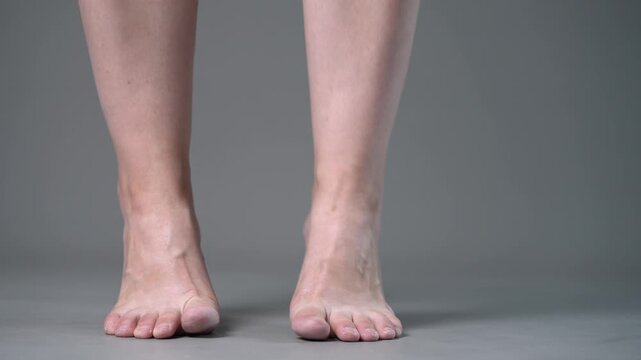 Individual leg training on a gray studio background, bare feet, demonstrating foot position and stability