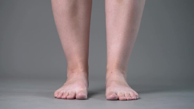 Individual leg training on a gray studio background, bare feet, demonstrating foot position and stability