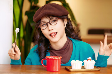 Beautiful Asian woman sitting in a coffee shop eating cake and drinking coffee on a winter afternoon