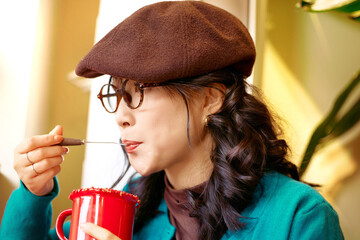 Beautiful Asian woman sitting in a coffee shop eating cake and drinking coffee on a winter afternoon