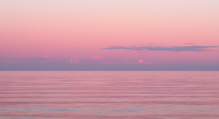 Fototapeta premium Serene ocean view at sunset with pastel pink sky and calm waters 