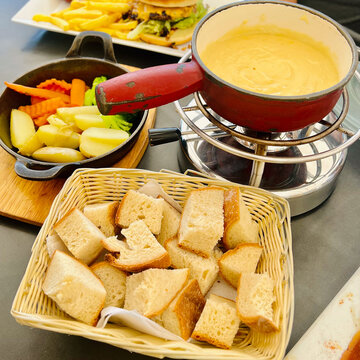 Cheese fondue on rechaud in Switzerland with bread and vegetables potatoes and carrots