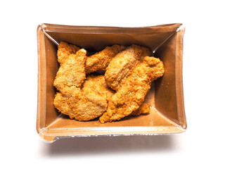 Uncooked chicken goujons or tenders in a card board box on white background. Popular classic chicken dish made from pieces of breast and breadcrumbs. Traditional ready to cook poultry product.