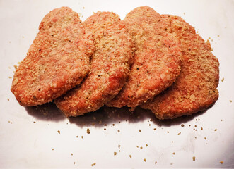 Lamb uncooked steak coated in Arabic Harissa style herbs and spices on stainless metal tray on wooden table. Red minced meat. Fine butcher style burgers ready for cooking.