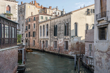 Fototapeta premium motorboat sailing away in canal with historical buildings, Venezia, Italy
