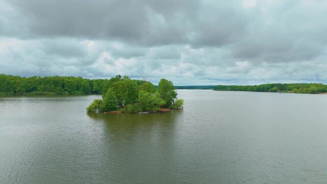 Drone footage capturing the serene beauty of the Trebon pond system in South Bohemia, Czech Republic. The shot features a tranquil lake with a lush green island, showcasing the unique natural landscap
