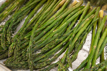 Cooked asparagus on a metal baking sheet. Roasted green vegetable for salad