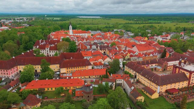 aerial perspective showcases the historic town of Třeboň in the South Bohemian Region of the Czech Republic. This footage captures the distinctive red tiled roofs, charming architecture, and the surro