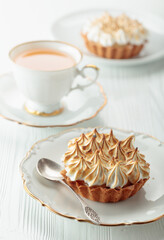 Meringue lemon tart on a white wooden table.
