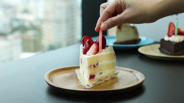 Hand Placing Candle on Japanese Strawberry Shortcake Slice