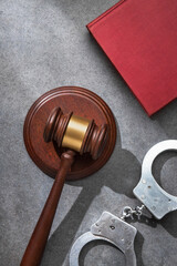 Judge gavel on sound block, handcuffs and Law book on a gray stone surface. Symbolizes courtroom...