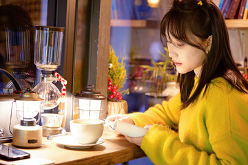 Oriental beauty drinking coffee in a coffee shop on a winter night