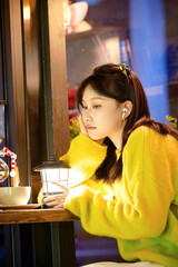 Oriental beauty drinking coffee in a coffee shop on a winter night