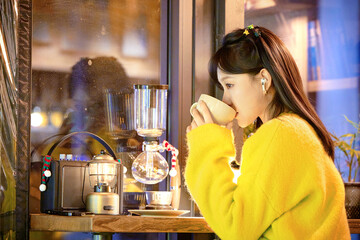 Oriental beauty drinking coffee in a coffee shop on a winter night