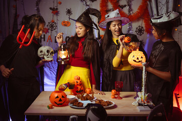 Asian man and woman celebrating Halloween, pumpkins at night, Halloween banner background for holiday activities.