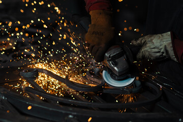 Intense sparks fly off the angle grinder as a worker shapes a custom wrought iron piece in a dramatic close-up view.