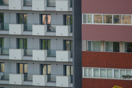 Fachada de edificios residenciales modernos con balcones blancos, ventanas y paneles de colores en contraste.