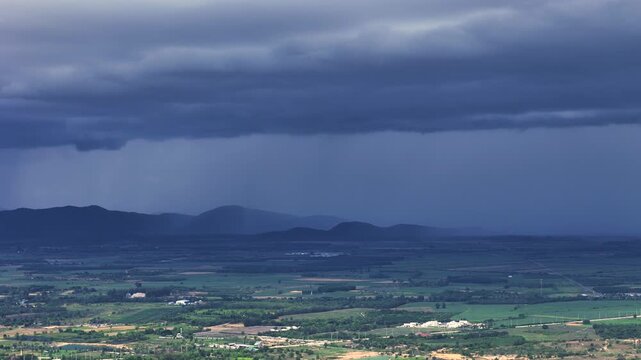 Wide rain band blankets horizon over mountains in tropical countryside during wet season